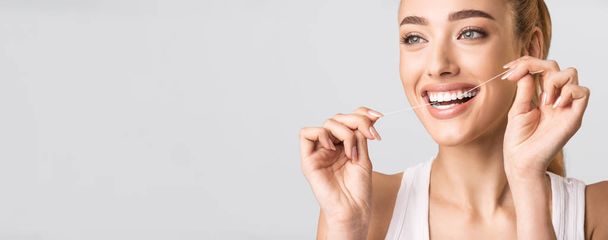 Uśmiechnięta kobieta nici dentystycznej idealne zęby stojące na szarym tle, Panorama - Zdjęcie, obraz