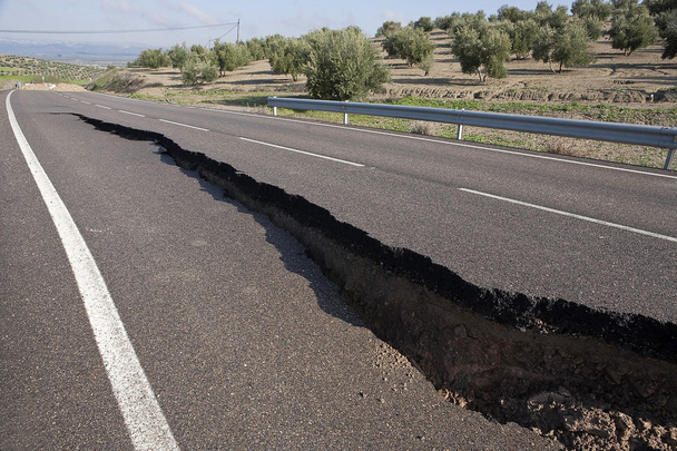 asfaltweg met een barst veroorzaakt door aardverschuivingen - Foto, afbeelding