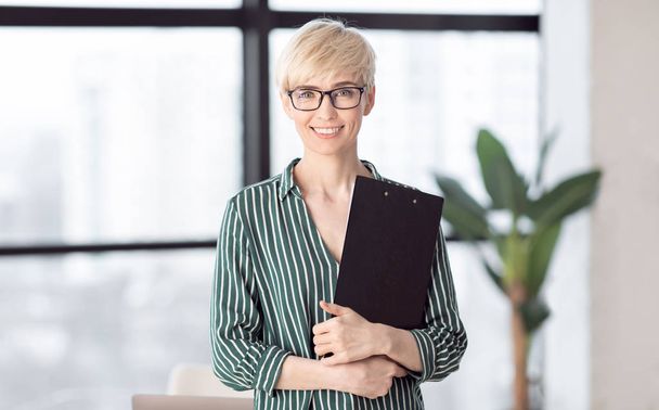 Successful Woman Holding Folder Smiling To Camera Standing In Office - Foto, Imagem