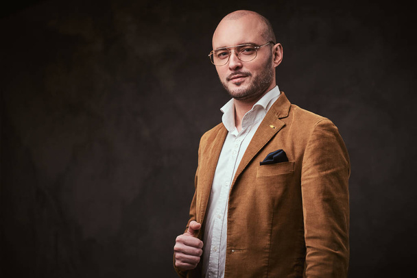 Successfull bald businessman posing in a studio wearing stylish velvet jacket, white shirt and glasses - Fotoğraf, Görsel