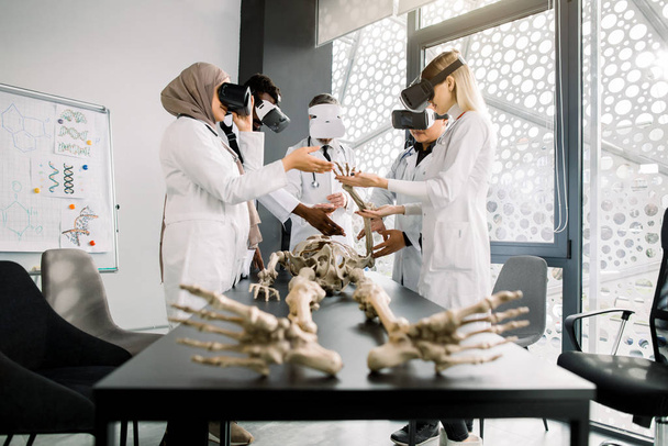 Male professor teacher using Virtual Reality Glasses to teach skeleton anatomy for multiethnic students in class. Education, VR, Tutoring, New Technologies and Teaching Methods concept. - Photo, image