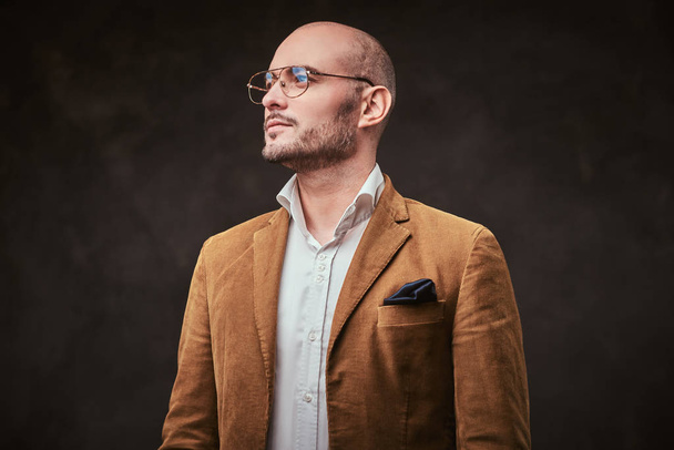Sikeres kopasz üzletember pózol egy stúdióban elegáns bársony kabát, fehér ing és szemüveg - Fotó, kép