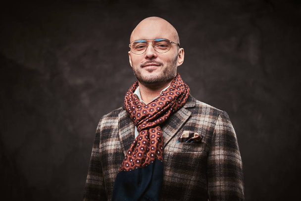 Succesvolle stijlvolle zakenman poserend in een studio met geruite jas, bril en sjaal - Foto, afbeelding