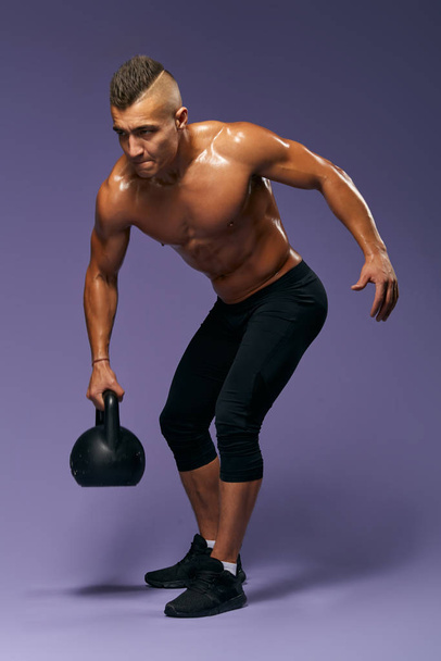 strong sweaty wet sportsman working out with kettlebell - Foto, imagen