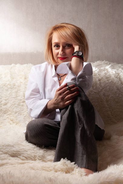 Portrait of an attractive middle-aged woman. Homemade portrait on the couch, middle-aged blonde. - Fotó, kép