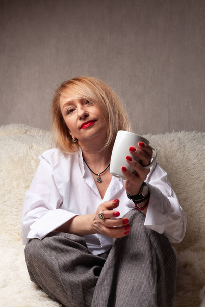 Portrait of an attractive middle-aged woman. Homemade portrait on the couch, middle-aged blonde. - Фото, зображення