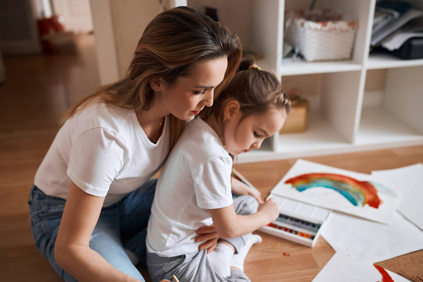 young woman giving advice recommendations while her little kid is painting - Photo, image