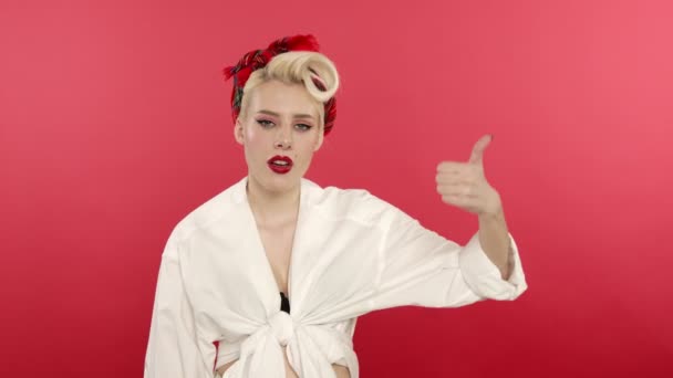 sceptische pin up meisje tonen duim naar beneden op roze achtergrond - Video