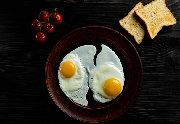 breakfast of scrambled eggs with fresh tomatoes and two slices of bread on a dark background. - Fotoğraf, Görsel