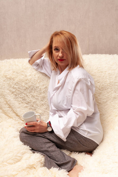 Egy vonzó középkorú nő portréja. Házi készítésű portré a kanapén, középkorú szőke. - Fotó, kép