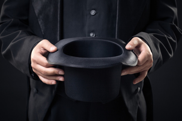 closeup of top hat in magician hands isolated on dark background - Photo, Image