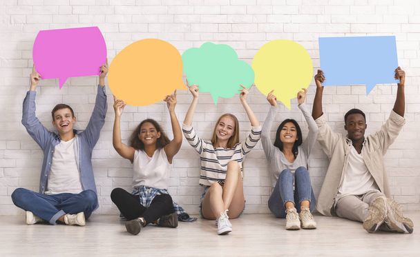 Students in casual clothes holding colorful speech bubbles - Fotoğraf, Görsel