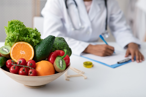 Afro lady nutritionist doctor writing vegetable diet plan - Photo, Image
