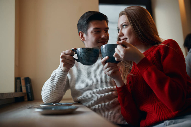 Hipster couple drinking yummy coffee, sitting next to each other - Фото, зображення