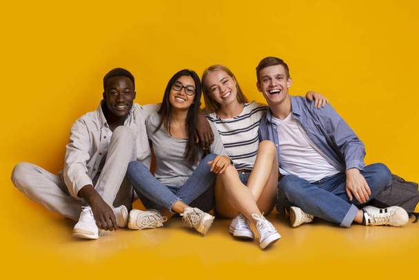 Estudantes felizes posando sobre fundo estúdio amarelo
 - Foto, Imagem