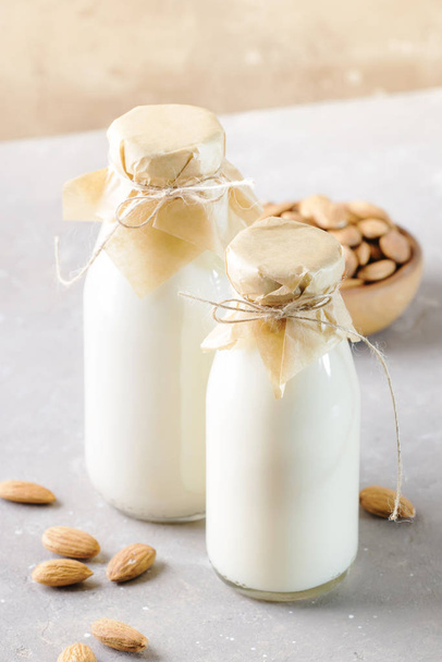 Vegan almond milk and cream in bottles, closeup, brown background. Non dairy alternative milk. Healthy vegetarian food and drink concept. Copy space - Photo, Image