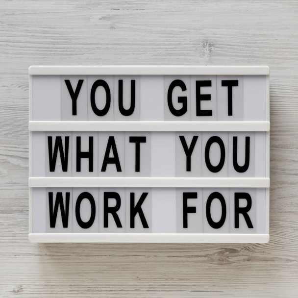 'Usted consigue lo que usted trabaja para' palabras en un tablero moderno en una w blanca
 - Foto, Imagen