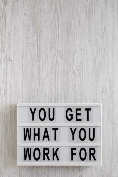 "Du bekommst, wofür du arbeitest" steht auf einer modernen Tafel auf weißem Grund. - Foto, Bild