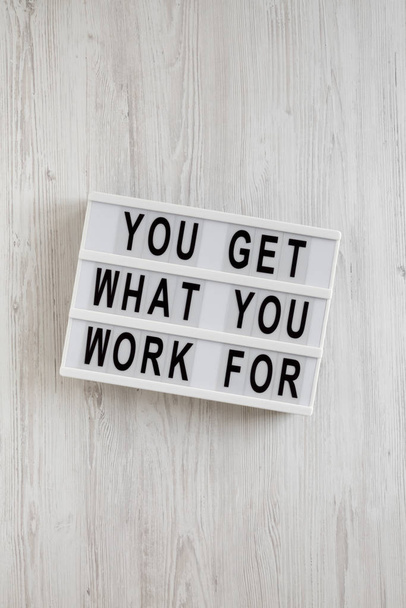 'You get what you work for' words on a lightbox on a white woode - Fotó, kép