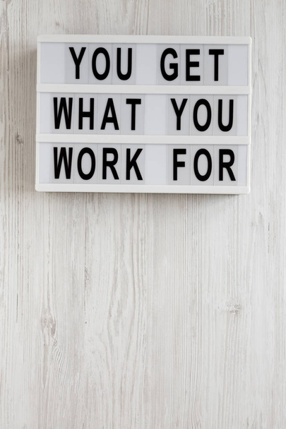 'You get what you work for' words on a lightbox on a white woode - Фото, изображение