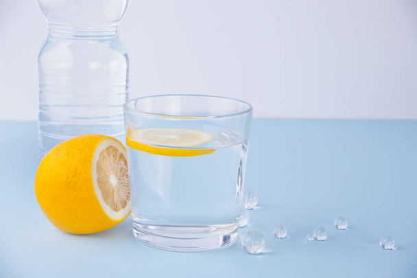 Glass of water, bottle and lemon fruit on the blue table. - Fotoğraf, Görsel