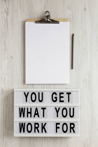 'Je krijgt waar je voor werkt' woorden op een lichtbak, klembord met  - Foto, afbeelding