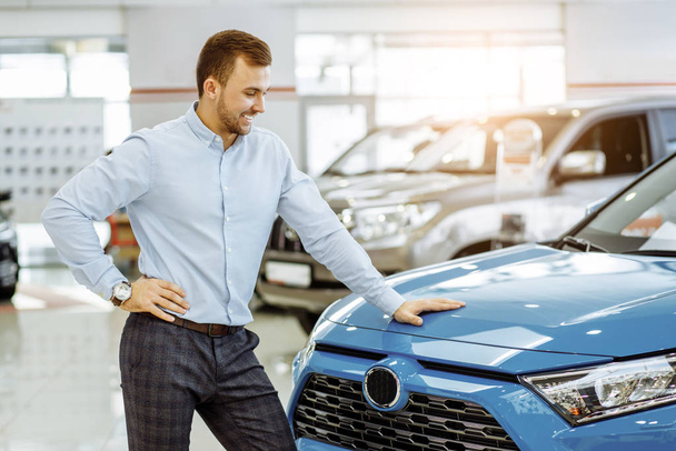 side view on handsome guy looking at new auto in dealership - Foto, imagen