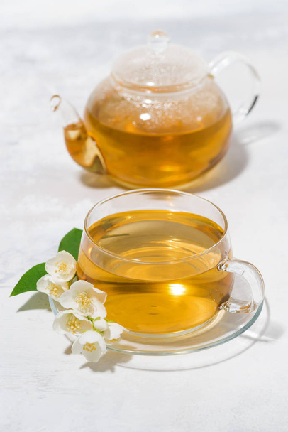 glass cup and teapot with jasmine green tea on white background - 写真・画像