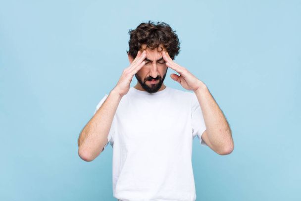 young crazy bearded man looking stressed and frustrated, working under pressure with a headache and troubled with problems against flat wall - Foto, imagen