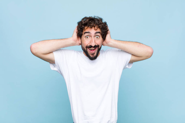 young crazy bearded man looking happy, carefree, friendly and relaxed enjoying life and success, with a positive attitude against flat wall - Foto, Imagem