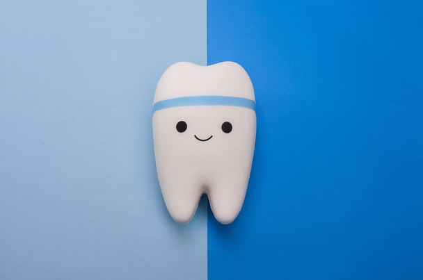 Cheerful smiling tooth on a blue background with copy space.  - Valokuva, kuva