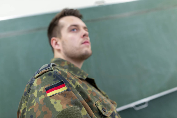 Duitse soldaat staat in een klaslokaal. Duits woord Bundeswehr, betekent Duits leger. - Foto, afbeelding