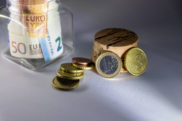 Avrupa banknotları ve avro sikkelerine sahip cam kumbaralar seyahat, tatil, özel yatırım ve nakit için tasarrufların yanı sıra yoksulluk ve düşük maaş ve Avrupa 'daki yoksul insanların düşük maaşlarını gösteriyor - Fotoğraf, Görsel