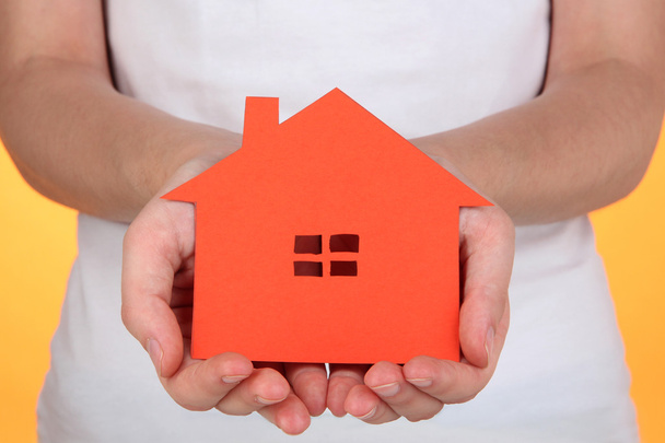 Paper house in hands on orange background - Photo, Image
