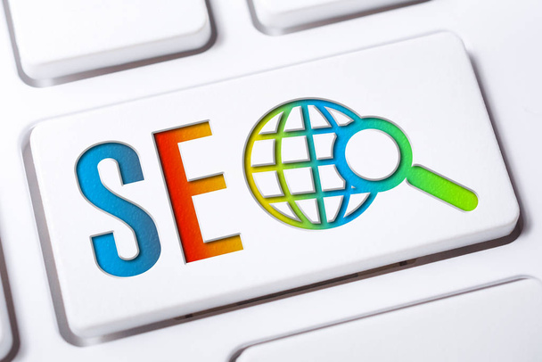 Kolorowe Seo Search Engine przycisk optymalizacji z Globe i szkło powiększające na białej klawiaturze, Business Marketing Concept - Zdjęcie, obraz