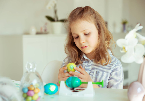 Cute little blonde girl painting Easter eggs - 写真・画像