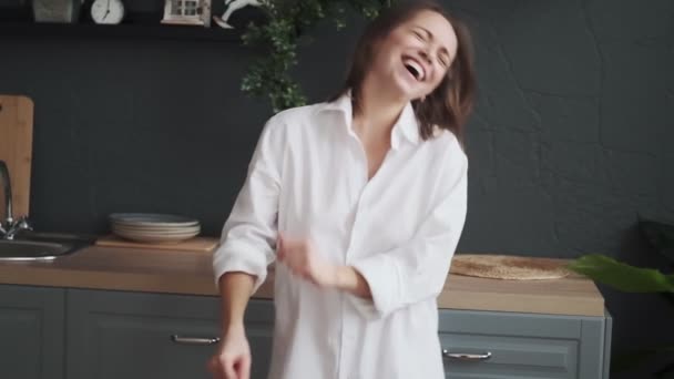 girl carelessly dances and laughs. young woman is having fun dancing in the kitchen - Filmmaterial, Video