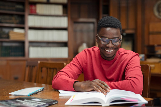 Happy university student reading in library - Foto, imagen