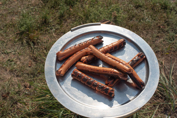 Grillezett kolbászt és húst tartalmazó fémtálcákkal ellátott pult. Élelmiszer és főzés - Fotó, kép