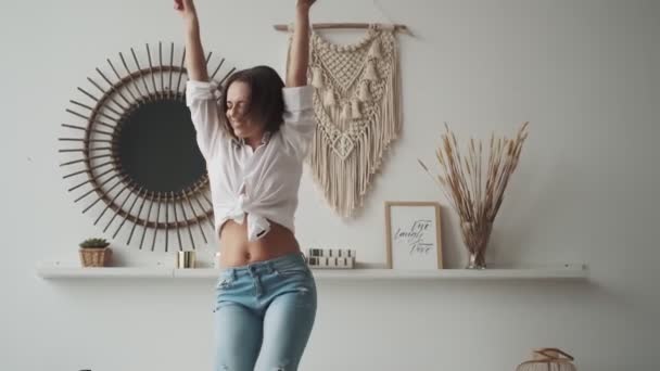 Ευτυχισμένο κορίτσι που διασκεδάζει χορεύοντας στο σπίτι. νεαρή γυναίκα ανέμελη χορεύει με τα χέρια σηκωμένα - Πλάνα, βίντεο