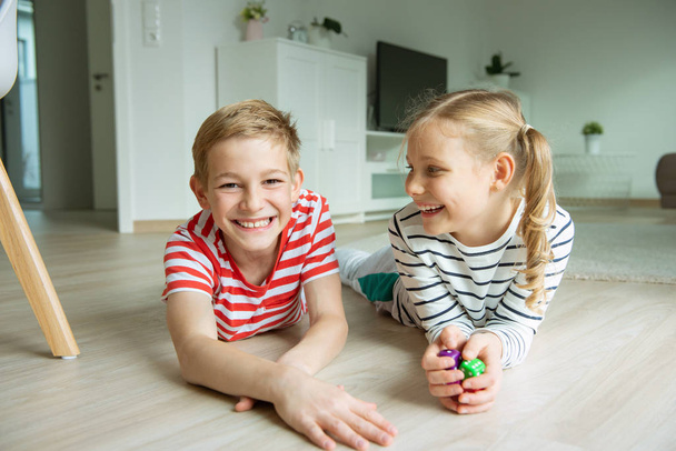 Portrait of two cheerful children laying on the floor and playin - Foto, immagini