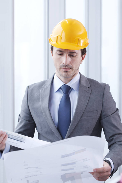 Architect in hardhat with blueprint - Foto, afbeelding