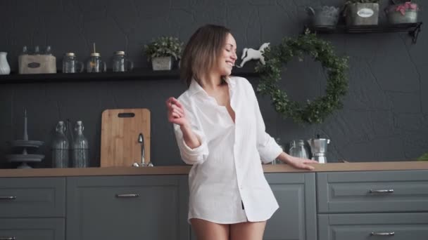 happy woman carefree dancing in the kitchen in the early morning. girl is dancing funny and smiling - Filmati, video