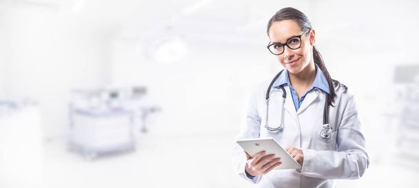 Médico médico mujer sosteniendo la tableta PC en frente de la sala de cirugía
 - Foto, Imagen