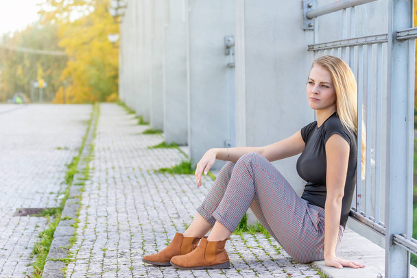 Pensive beautiful young girl is sitting on the bridge - Foto, Imagen