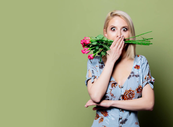 Beautiful blonde woman in dress with roses on green background - Фото, зображення