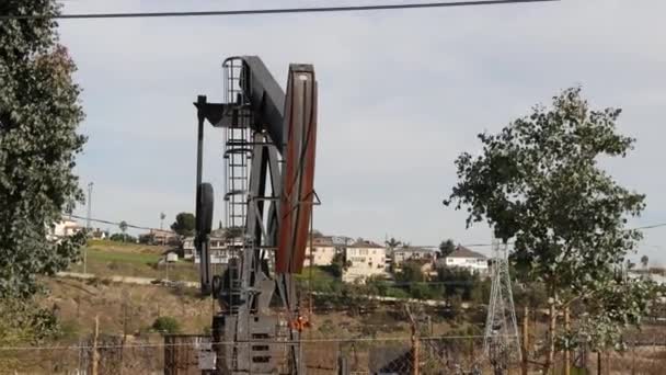 工業都市景観。ロサンゼルスのLa Brea Inglewood 。フェンスの後ろで作動するポンプジャック。掘削リグは原油を抽出します。ピストンを作動させたオイル鉱山機械。石油・ガス産業 - 映像、動画