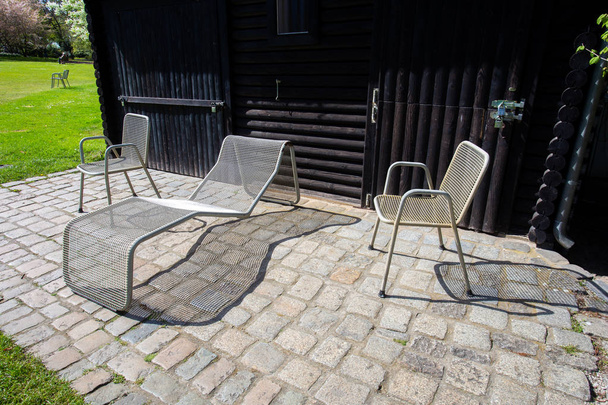 Typical sunbed and two metal mesh chairs in the park - Фото, зображення