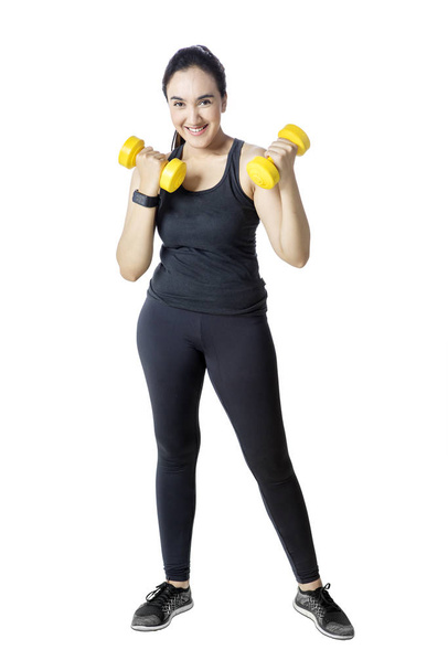 Woman exercising with dumbbells in studio - Фото, изображение