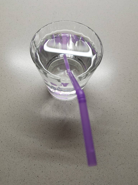 Full glass of water with purple drinking tube on a marble table - Photo, Image